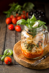 Italian Pasta with tomato sauce, mushrooms, peas and cheese in a jar. Food for work and office
