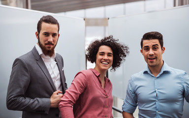 Young businesspeople standing in office, looking at camera.
