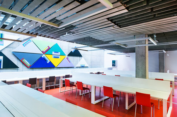 An interior of a modern spacious study room in a library or office.