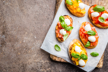 Bruschetta with tomato, basil and mozzarella cheese on wooden board top view. Traditional italian appetizer or snack, antipasto
