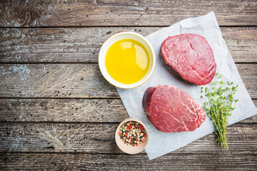 Raw marbled meat steak Filet Mignon with seasonings over stone background, top view.