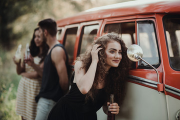 A group of friends standing outdoors on a roadtrip through countryside, holding bottles.