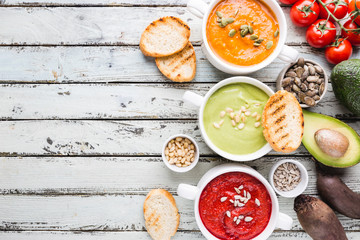 Variety of different colorful vegetable cream soups in a bowls, top view. Concept of healthy eating or vegetarian food.