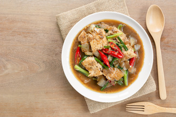 top view of stir fried chicken with black pepper sauce and vegetable in a ceramic dish on wooden table. homemade style hot and spicy food concept.