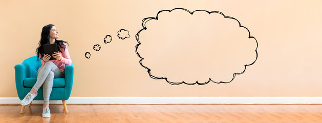 Blank speech bubble with young woman holding a tablet computer in a chair