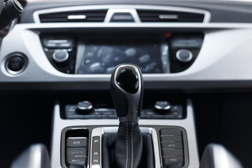 Fototapeta na wymiar Selector automatic transmission with perforated leather in the interior of a modern expensive car. The background is blurred