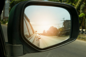 Traveling on the road, view from the side mirror with orange light.In the country.