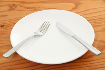 white dish on the wooden table with cutlery meaning PAUSE