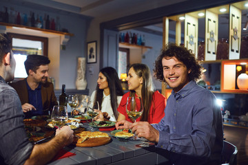 Man with a glass against the background of friends in a restaurant.