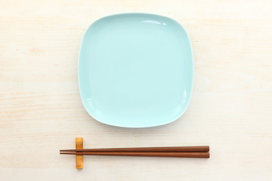 empty blue dish with chopsticks on the whtie wooden table
