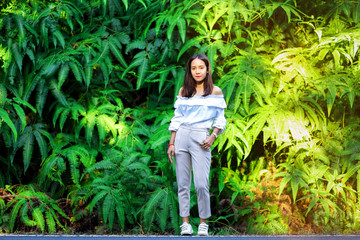 Asian woman with fern bush in background
