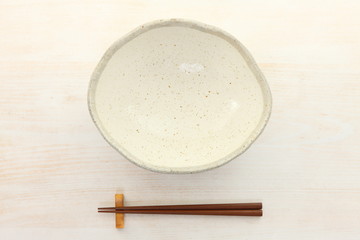 Fototapeta na wymiar empty clay dish with chopsticks on the whtie wooden table