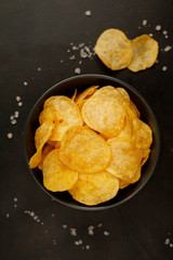 Crispy chips in a bowl on a stone background