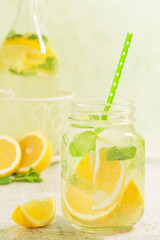 Fresh lemonade in mason jar. Mint and lemon halves on blue fresh background.Fresh lemonade in mason jar. Mint and lemon halves on yellow fresh background