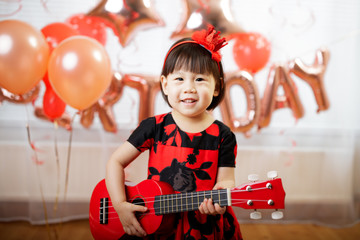 toddler girl  play ukulele celebrating her third birthday at home