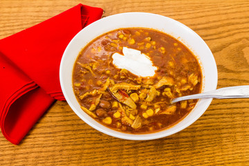Chicken Enchilada Soup with Dollop of Sour Cream on Rustic Table