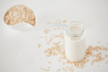 Top view of organic homemade oat milk with bowl of rolled oats on kitchen table.