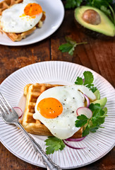 Savory waffles with egg on wood background. Flat lay, top view, copy space.