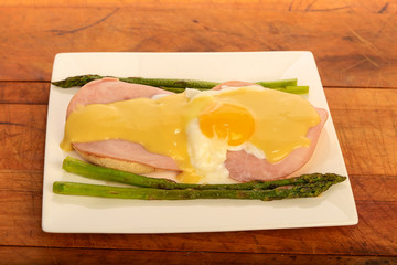 Elegant Egg Benedict Plate on Rustic Wooden Table BG