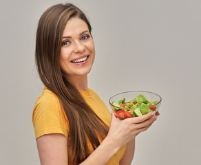 Smiling woman holding salad in glass bowl.