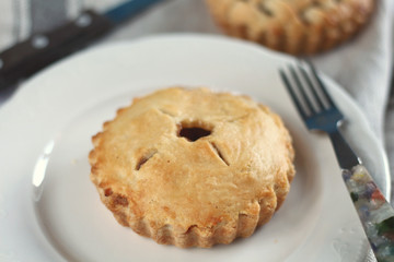 Traditional rustic homemade american  apple cherry pie on white plate with fork