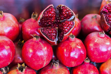 Pomegranate fruit lay stacked and peeled pomegranate on top.