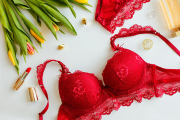 Red women underwear and spring Tulips flowers in pink tones . Red bra and pantie. Copy space. Beauty, fashion blogger concept. Romantic lingerie for Valentine's day temptation.Erotic concept.