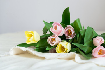 Spring flowers. Bouquet of pink yellow tulips on beige fabric background. Mother's Day, Valentines Day and Happy birthday background, side view