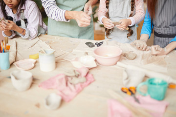 High angle closeup of children making handmade ceramics in pottery workshop, copy space
