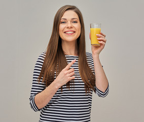 woman wearing striped shirt holding glass with orange juice and pointing finger.