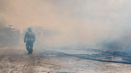 Fire trucks and firefighters in the smoke from the fire