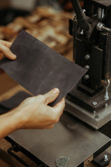 Man holding leather craft and working. Press machine in the workshop for doing the embossed logo and letters on the leather product that heats the cliche and squeezes the desired image on the material
