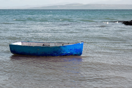 Small blue rowing boat moored in the sea