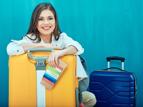 Smiling young woman with two suitcase shows thumb up.