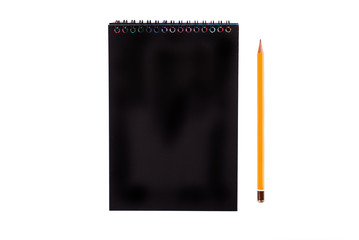 Top view of closed black cover notebook with pencil on white desk background