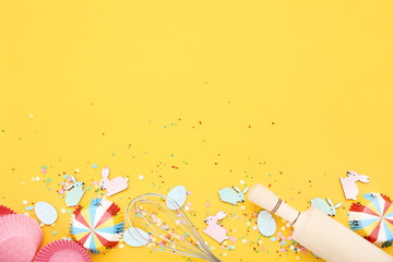 Easter rabbits and eggs with kitchen utensil on yellow background