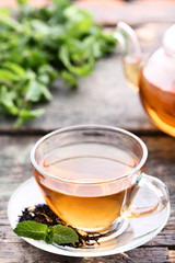 Cup of tea with mint leafs on grey wooden table