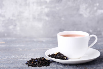 Cup of tea and dry leafs on grey wooden table