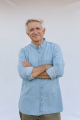 Senior man with crossed arms on white background