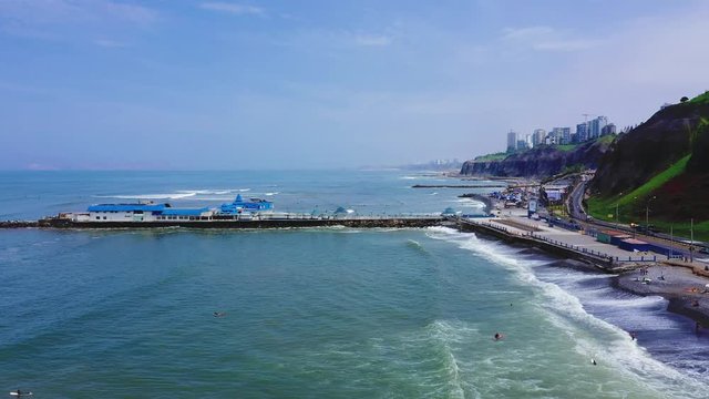 Drone aerial view of La Rosa Nautica restaurant by the sea in Makaha Beach. Group of surfers learning to surf in a bright summer day at Miraflores district, Lima, Peru.