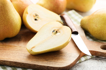 Ripe pears with cutting board and knife on wooden table