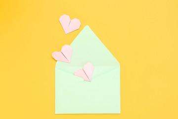 Green envelope with paper hearts on yellow background