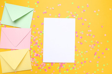 Colorful envelopes with blank paper and confetti on yellow background