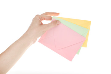 Female hand with colorful paper envelopes on white background