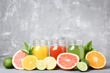 Citrus juice in glass jars with fruits on grey wooden table