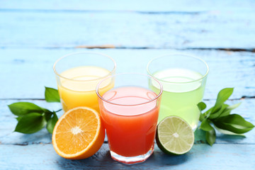 Citrus juice in glasses with fruits on blue wooden table