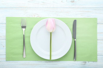 Kitchen cutlery with plate and tulip flower on wooden table