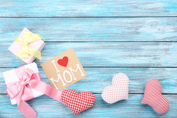 Greeting card with gift boxes and fabric hearts on blue wooden table