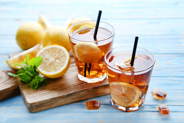 Ice tea in glasses with lemon and mint leafs on wooden table