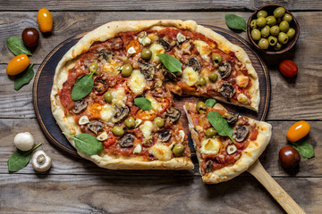 pizza with mushrooms, tomatoes, olives and spinach and goat cheese on wooden background